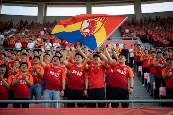 球场看台上球迷举旗为球队加油的现场画面